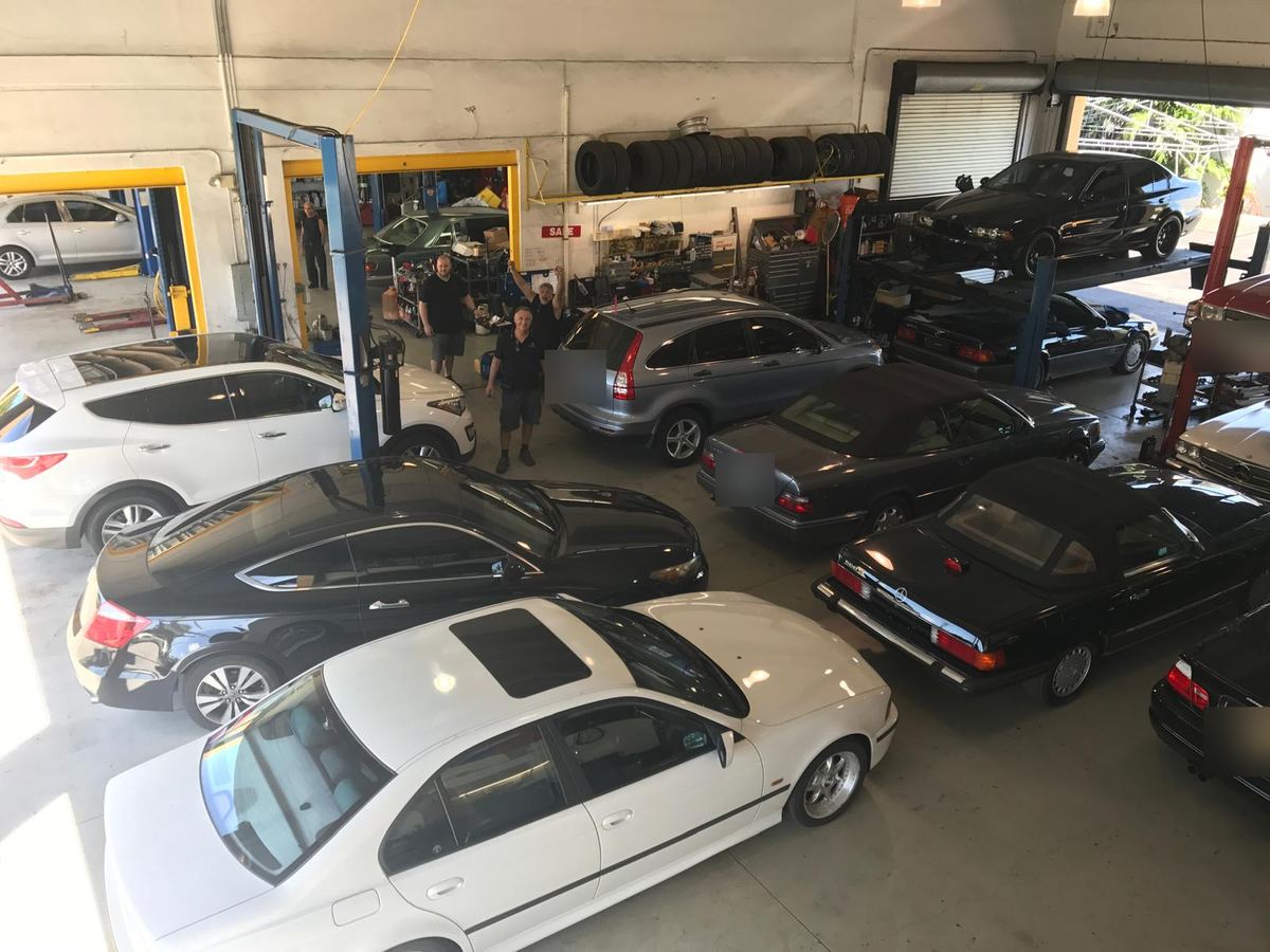 The Auto Star Co. crew waving in the shop in Hallandale Beach