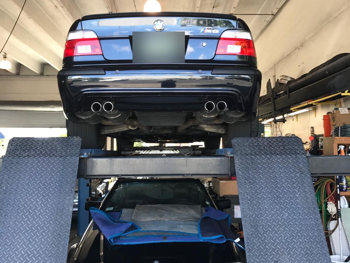 BMW M5 on a lift above a Mercedes-Benz SL at Auto Star Co. in Hallandale Beach