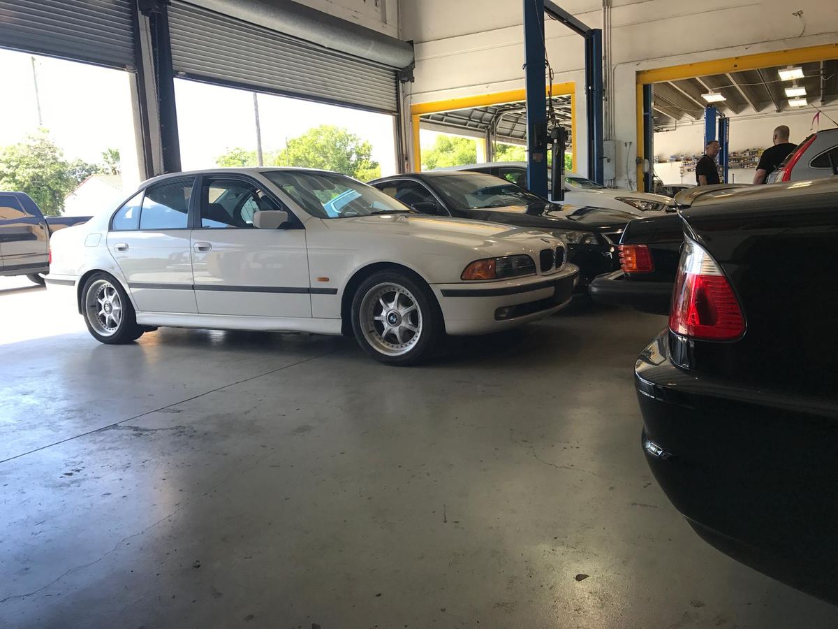 White BMW 5 Series by the open bay doors at Auto Star Co. in Hallandale Beach